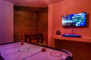 a room with a tv and a ping pong table at Il-Kampnar Gozo Farmhouse with Private Pool in Sannat