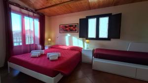 a bedroom with two beds with red sheets and windows at Gaia Holidays Apartments in Cefalù