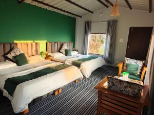 a bedroom with two beds and a green wall at Neo Resort in Kanatal