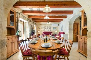 a large dining room with a wooden table and chairs at Il-Kampnar Gozo Farmhouse with Private Pool in Sannat