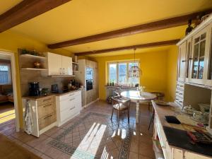 a kitchen with yellow walls and a table and chairs at Chiemgauer Landliebe in Höslwang