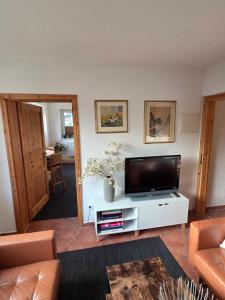 a living room with a flat screen tv on a white cabinet at Kapitänshaus - Terrassenstube in Barth