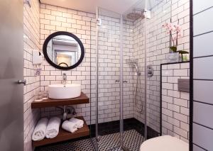 a white tiled bathroom with a sink and a mirror at Prima Tel Aviv Hotel in Tel Aviv