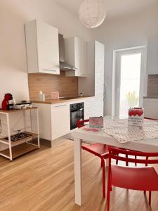 a kitchen with a white table and red chairs at Petali Rosa - Dimora Antica Roma in Polignano a Mare +7 photos