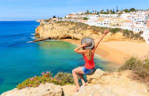 a woman sitting on a cliff overlooking a beach at Luna Hotel da Oura in Albufeira