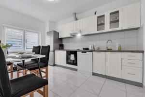 a kitchen with white cabinets and a table with chairs at Apartment Green Valley in Imotski