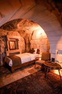 a bedroom with a bed and a chair in a stone room at Lost City Cappadocia in Nar