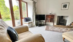 a living room with a couch and a television at The Coach House in Saint Fillans