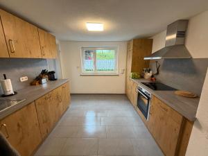 a large kitchen with wooden cabinets and a window at Tälealpakahof in Alpirsbach