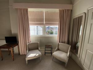 a living room with two chairs and a desk and a window at The Cavendish Arms in Cartmel