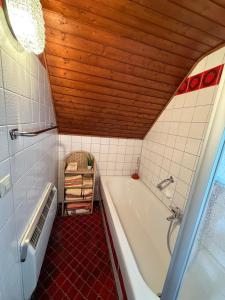 a bathroom with a white tub and a wooden ceiling at Tälealpakahof in Alpirsbach +59 photos