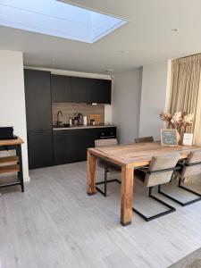 a dining room with a wooden table and a kitchen at Casa Nova Arnhem in Arnhem