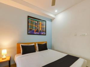 a bedroom with a bed and a painting on the wall at Super Townhouse Qualia Prime in Hyderabad +24 photos