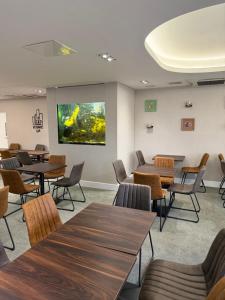 a waiting room with tables and chairs and a large screen at ICON Hotel in Luton
