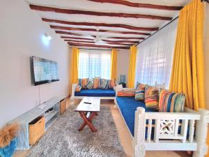 a living room with a blue couch and yellow curtains at Elna's Haven Diani Palms - 5min walk to the beach, serene and culinary services in Ukunda