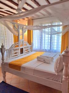a white bed with a canopy in a bedroom at Elna's Haven Diani Palms - 5min walk to the beach, serene and culinary services in Ukunda
