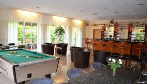 a billiard room with a pool table and chairs at Hotel Messeblick in Sarstedt