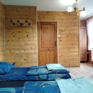 a bedroom with two beds and a wooden wall at Baza Warsztatowo-Edukacyjna K85 Komańcza in Komańcza