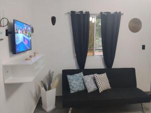 a living room with a black couch and a tv at Xamanai Playa Rincón in Castellalito