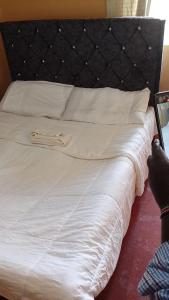 a bed with white sheets and a black headboard at Footprint Baringo in Marigat