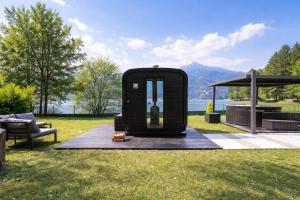 a black outhouse sitting on the grass in a field at Villa Ledro with Private Dock - Sauna - Hot Tub in Molina di Ledro