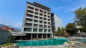a hotel with a swimming pool in front of a building at Soaltee Westend Lakeside Pokhara in Pokhara