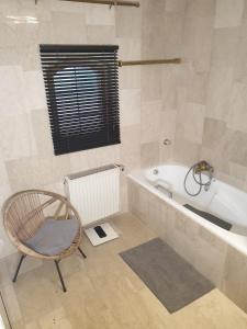 a bathroom with a chair and a bath tub at Traumhaus im Wald in Tutzing +8 photos