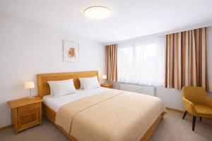 a bedroom with a bed and a chair and a window at Stadthotel Carinthia in Klagenfurt +69 photos