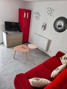 a living room with a red couch and a table at Studio cosy proche bourg et plages tout équipé in Plouhinec