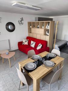 a living room with a table and a red couch at Studio cosy proche bourg et plages tout équipé in Plouhinec