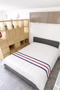 a bedroom with a bed with white sheets and wooden shelves at Studio cosy proche bourg et plages tout équipé in Plouhinec