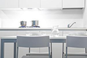 a kitchen with white counters and white chairs at meckisapartment in Nago-Torbole