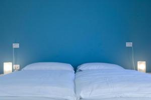 a bed with two white pillows and a blue wall at meckisapartment in Nago-Torbole