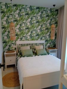 a bedroom with a bed with a tropical wallpaper at Baltic Park in Rozewie