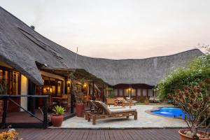 a villa with a thatched roof and a pool at Elephants Footprint Lodge in Colchester