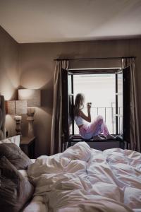 a woman sitting on a window sill looking out of a bed at Boutiquehotel Weisses Rössl in Innsbruck