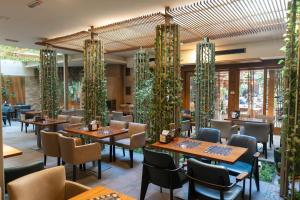 ein Restaurant mit Tischen, Stühlen und Pflanzen in der Unterkunft Hollywood Hotel in Sarajevo