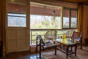 a room with a table and chairs and a door at Mud House Entire Cottage in Dharmsāla