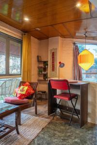 a living room with a desk and a red chair at Mud House Entire Cottage in Dharmsāla