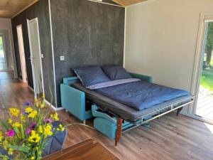 a bed in a room with a blue couch and flowers at Ferienhaus am See in Körba in Lebusa +24 photos