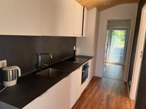 a kitchen with white cabinets and a black counter top at Ferienhaus am See in Körba in Lebusa