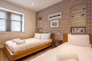 two beds in a room with wooden walls at Creewood - Elie in Elie