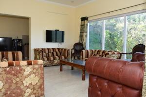 a living room with couches and a large window at Serenidad- The Cottage in Mukteshwar