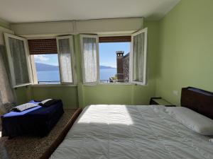 a bedroom with a bed and two windows at La vista dal borgo in Toscolano Maderno