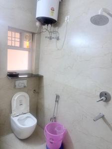 a bathroom with a toilet and a pink bucket at Serenidad- The Cottage in Mukteshwar +18 photos