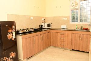 a kitchen with wooden cabinets and a black refrigerator at Serenidad- The Cottage in Mukteshwar