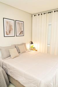 a white bedroom with a large white bed at Vinícola Villa Aurum in Corumbá de Goiás
