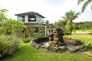 a garden with a pond in front of a house at Vinícola Villa Aurum in Corumbá de Goiás
