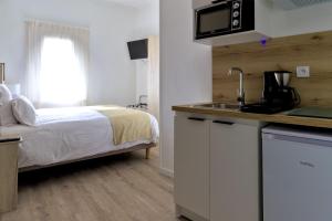 a bedroom with a bed and a kitchen with a sink at Hôtel Archipel in Balaruc-les-Bains