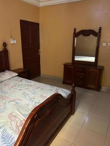a bedroom with a bed with a dresser and a mirror at Room 11 in Kololi